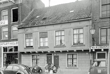 <p>Foto van het voormalige Schippers Gildehuis van vlak voor de sloop in de jaren '60 van de 20e eeuw. Later zou hier nieuwbouw in vergelijkbare vormgeving opgetrokken worden (B). Links het voormalige woonhuis (A) van de familie Schuttevaer (beeldbank RCE). </p>

